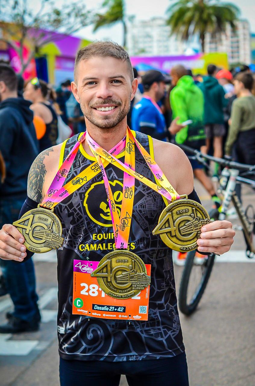 Arthur Mello segurando três medalhas de corrida